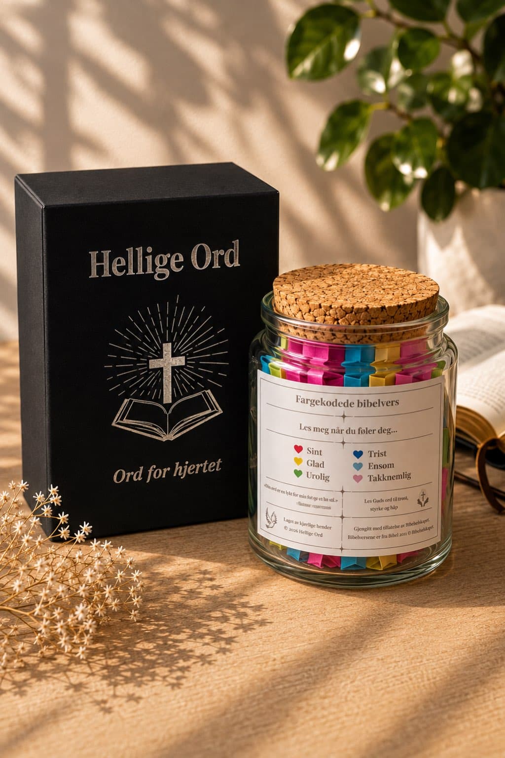 Bibelvers-krukke ved siden av svart gaveeske og åpen bibel i varmt naturlig lys